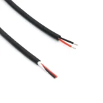 Material-library photograph of black-sheathed two-core cable samples with red and black insulated cores and stripped conductor ends.